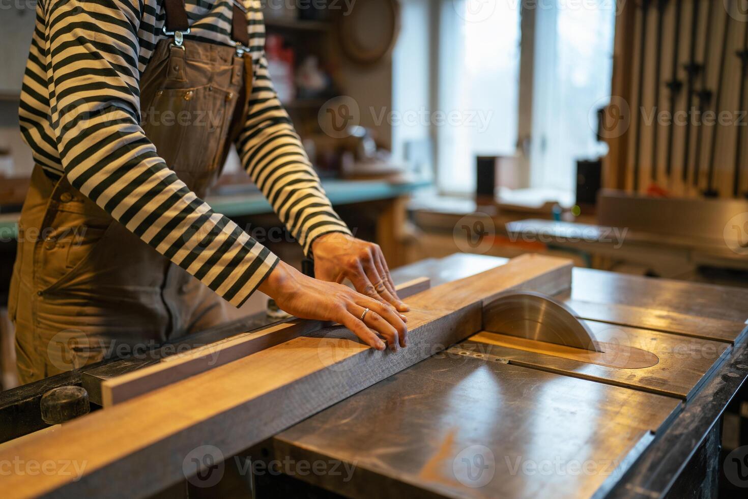 Carpenter hands with wood block on table saw, cut wood. Measuring and preparing beams for work photo