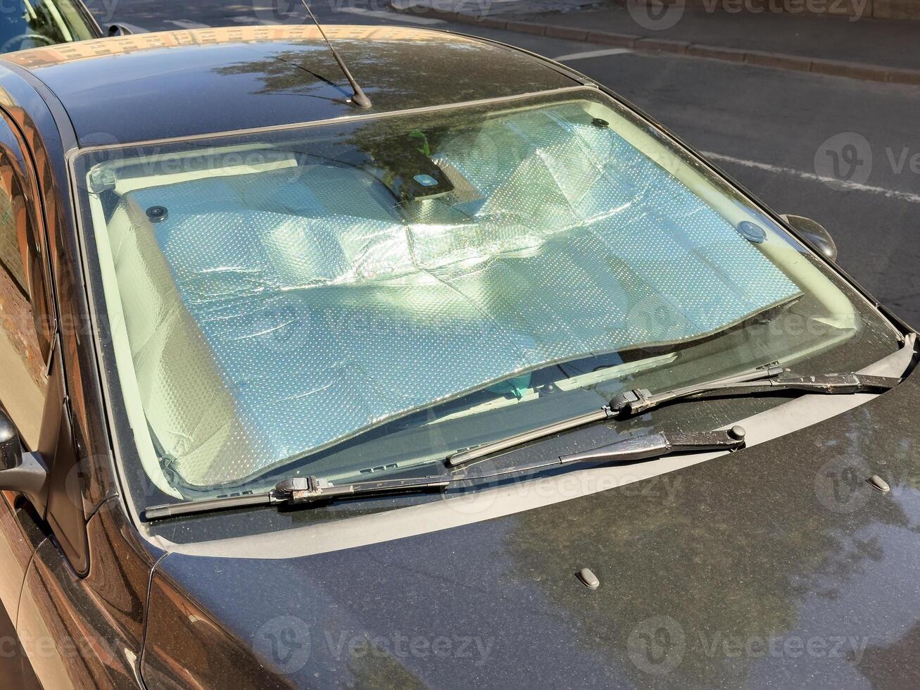 Closeup of protective reflective surface under the windshield of passenger car parked on hot day photo