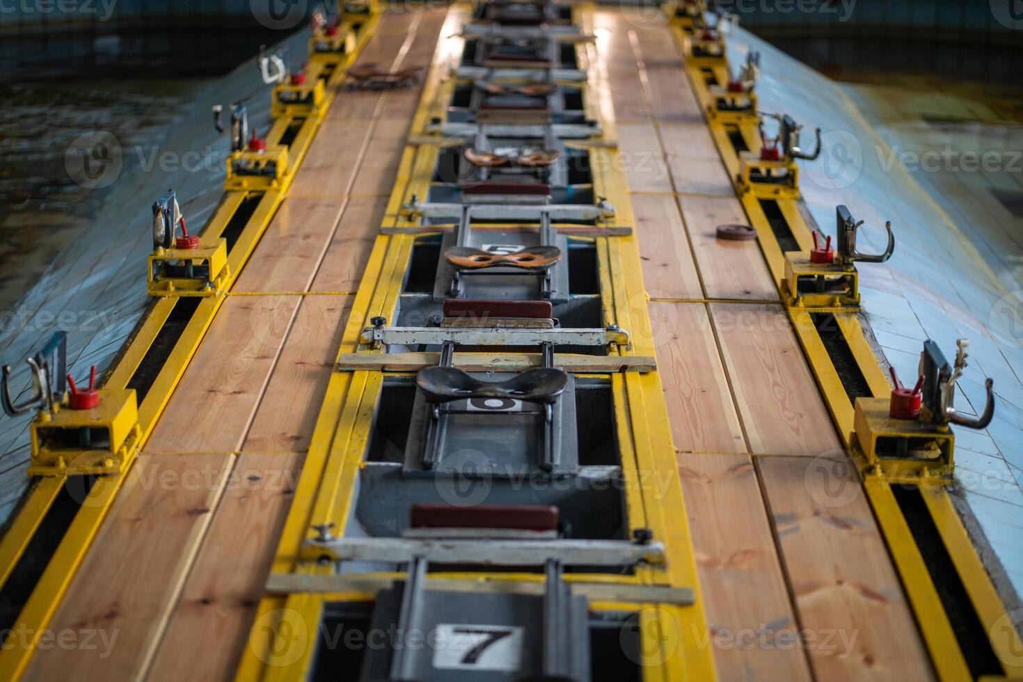 Rowing machine setup in pool, seats aligned for synchronized training. Water sports simulator photo