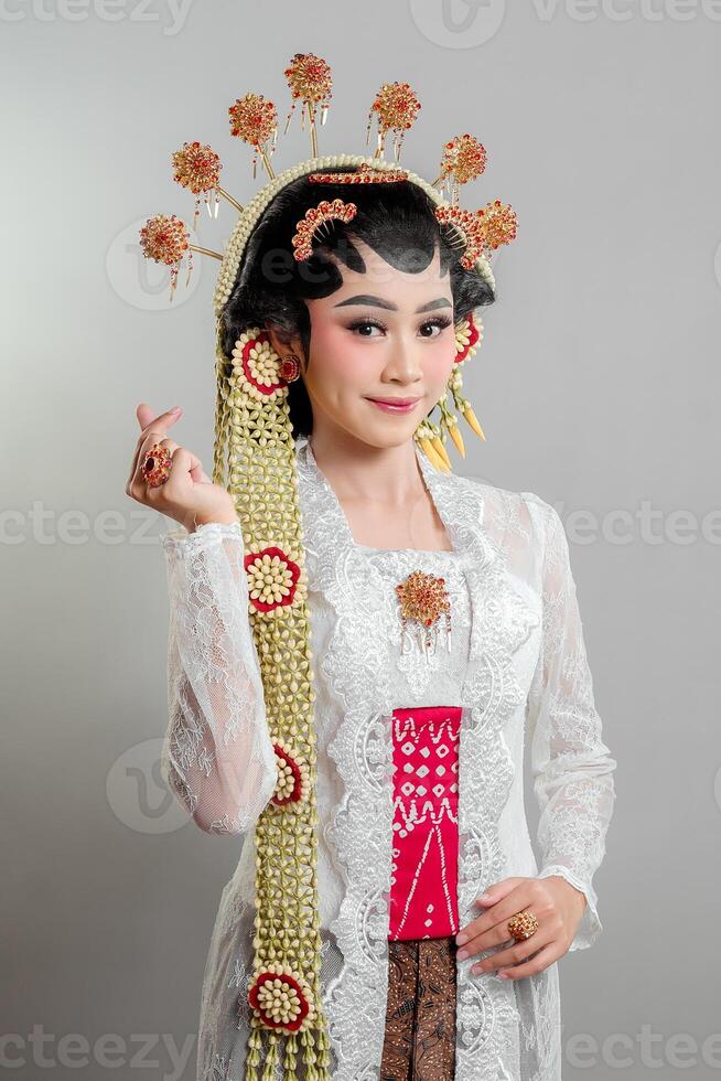 elegant Indonesian bride in traditional Solo Putri attire, wearing a lace kebaya, intricate golden accessories, and jasmine garlands, smiling gracefully. photo