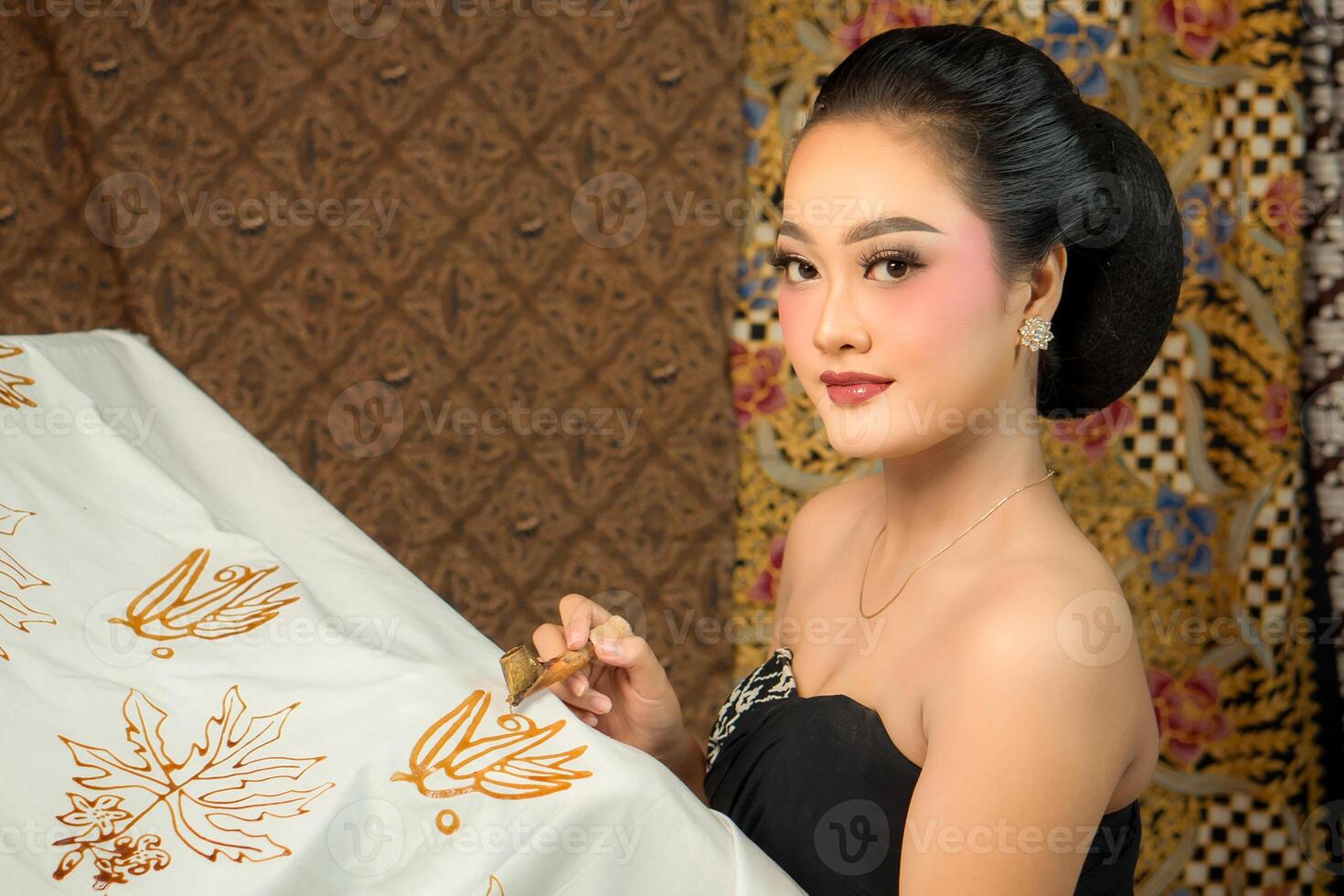 Indonesian young woman creating batik with a canting, wearing traditional attire. Elegant look, rich cultural heritage, and intricate patterns. Artistic craftsmanship of Southeast Asian textile art photo