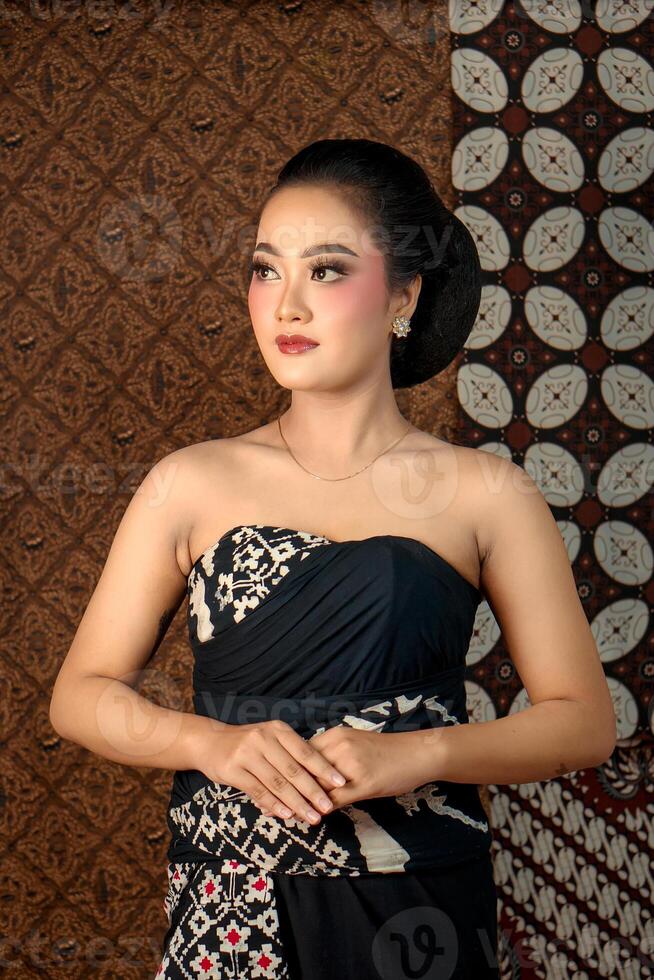 Beautiful Indonesian woman in traditional Javanese attire with elegant makeup and classic batik fabric. Cultural portrait with a graceful pose and rich heritage style photo