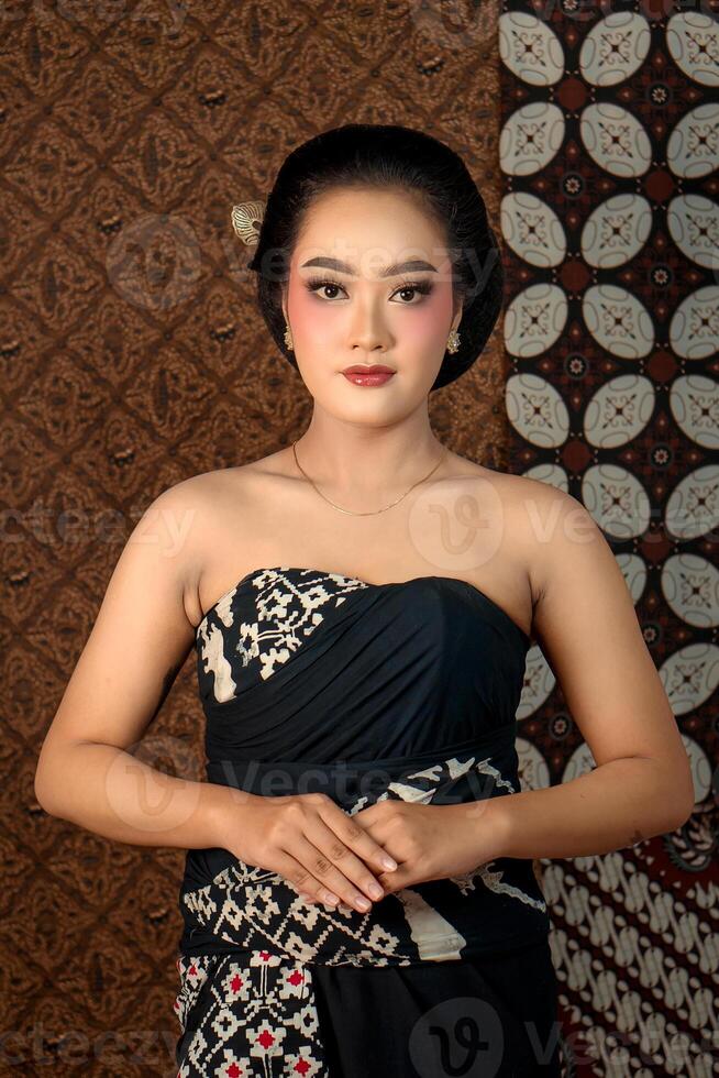 Beautiful Indonesian woman in traditional Javanese attire with elegant makeup and classic batik fabric. Cultural portrait with a graceful pose and rich heritage style. photo
