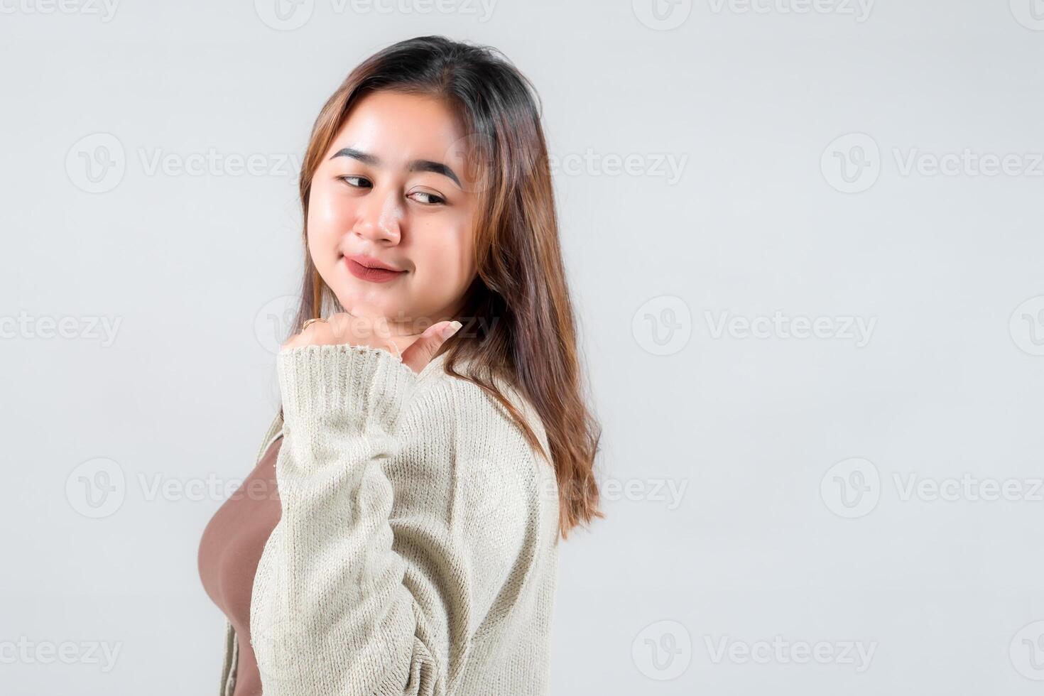 A young woman smiles playfully while looking over her shoulder, giving a thumbs-up gesture. Her casual outfit and cheerful expression make this image perfect for lifestyle and social media content. photo