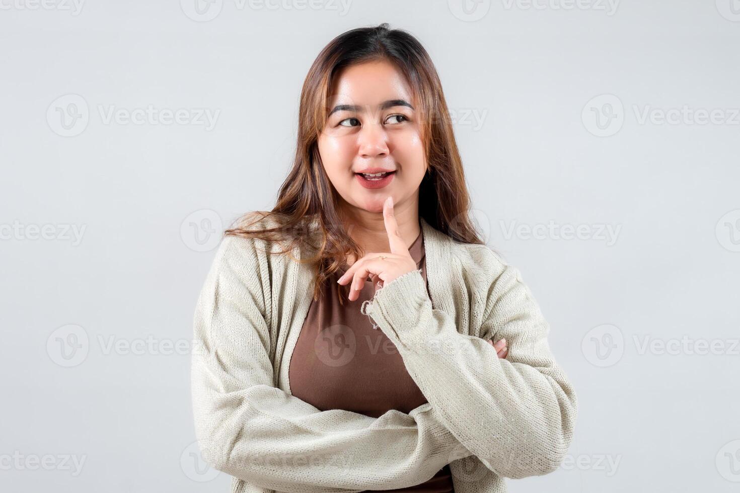 A playful young woman poses with a finger on her lips, suggesting secrecy. Her casual attire and expressive demeanor make this image ideal for lifestyle, social media, and creative projects. photo