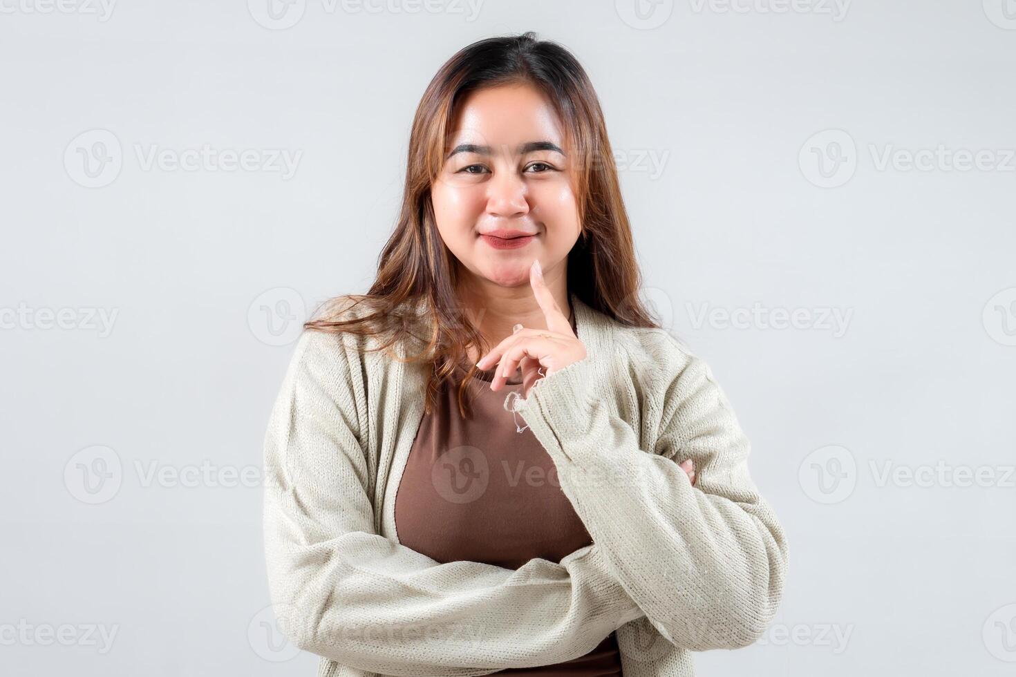 An playful young woman poses with a finger on her lips, suggesting secrecy. Her casual attire and expressive demeanor make this image ideal for lifestyle, social media, and creative projects. photo