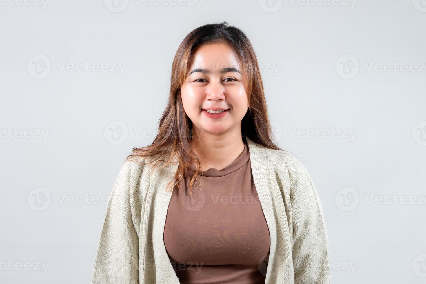 A cheerful young woman smiles confidently against a neutral background, showcasing her casual style. Perfect for lifestyle, fashion, and portrait photography needs. photo