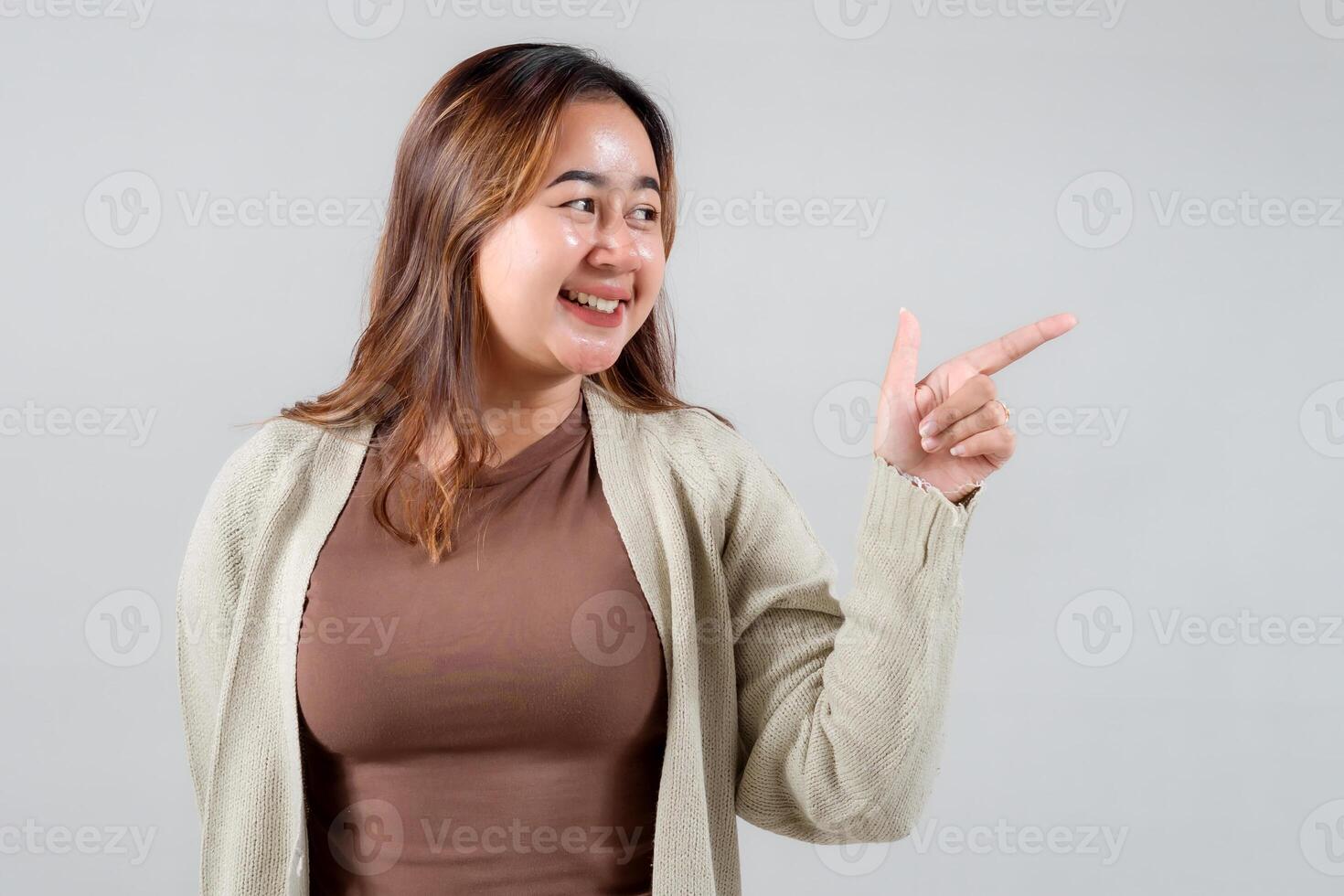 cheerful young woman points to the side with a bright smile, showcasing her casual style. This engaging image is perfect for lifestyle, social media, and creative projects that convey positivity photo