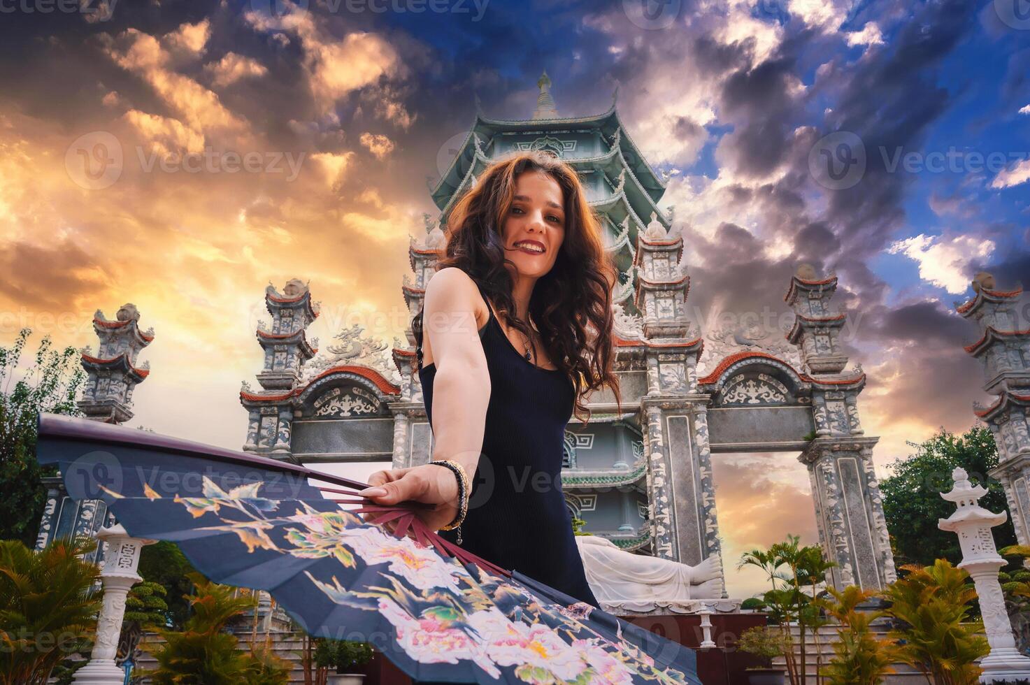 Portrait of a happy young woman tourist traveler with a fan at temple on Buddhist pagoda in Da Nang, Vietnam. Travel and tourism in Asia photo