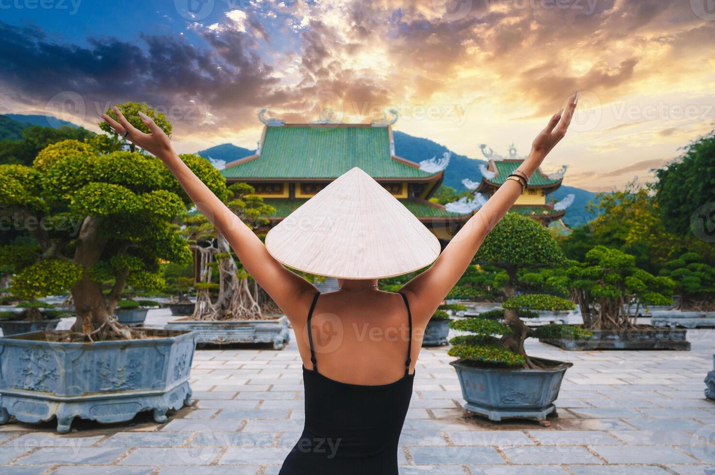 back of happy girl tourist traveler at a Buddhist temple at Linh Ung Pagoda in Da Nang in Vietnam at sunset. Concept of travel and tourism in Asia photo