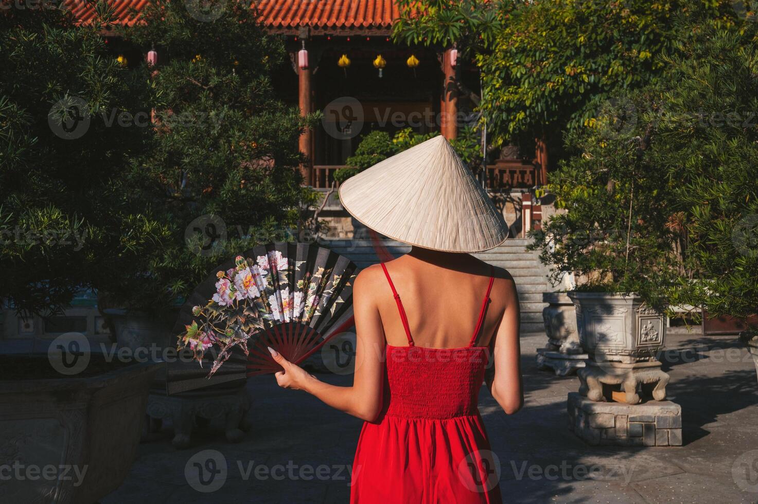 back of beautiful young woman tourist with fan in Non La hat in travel in Vietnam photo