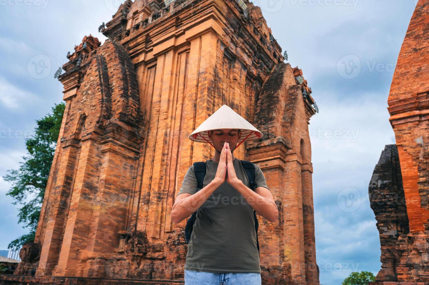 man in a Vietnamese cone hat non la prays at ancient Po Nagar Cham Towers in Nha Trang, Vietnam. The concept of travel in Asia photo