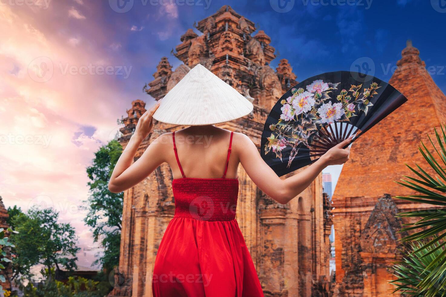 back of an Asian girl tourist traveler in a Vietnamese hat Non La with fan on Cham Towers of Po Nagar in Nha Trang in Vietnam in Asia photo