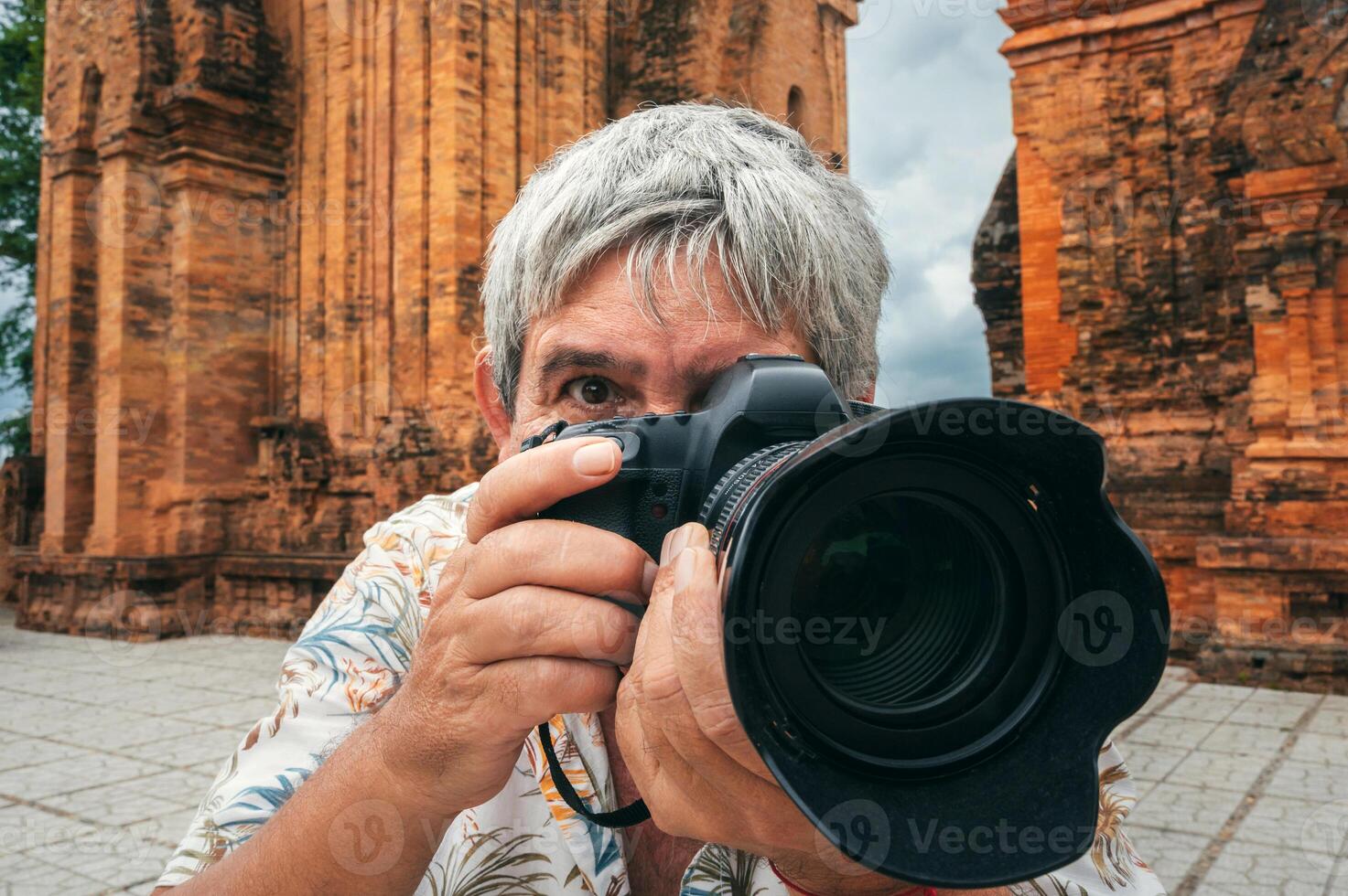 elderly man tourist traveling professional photographer with a camera takes pictures of landmarks at ancient Po Nagar Cham Towers in Nha Trang in Vietnam photo