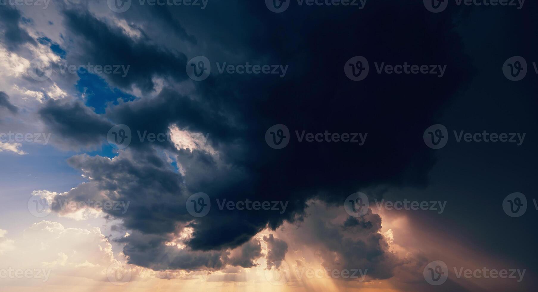 dark dramatic clouds in cloudy sky in a storm and rain at sunset photo