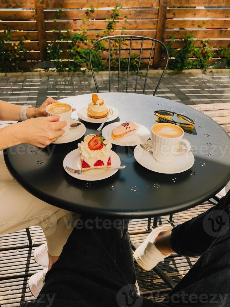 Two friends share peaceful coffee moment at outdoor cafe. Warm cafe ambiance with coffee cups and artistic pastries. inviting outdoor table, filled with sweet treats, sets mood for delightful break. photo