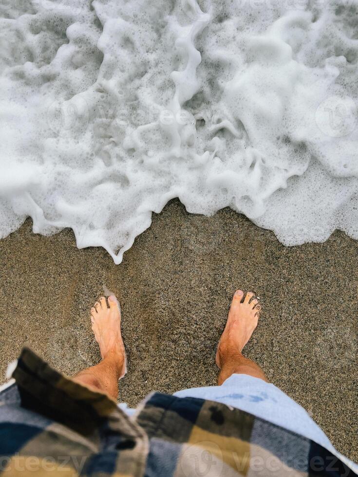 First-person view. Standing barefoot on warm sand, barefoot sensation meets ocean breeze, moment enhances connection to nature, barefoot steps embrace tranquility of shore. Feet sink, beach sand photo