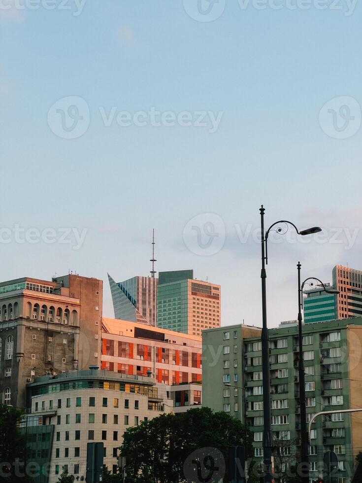 Warsaw skyline blending historic and contemporary architecture, silhouetted against warm sunset colors, revealing urban layering and contrasting building styles. Modern and historic buildings photo