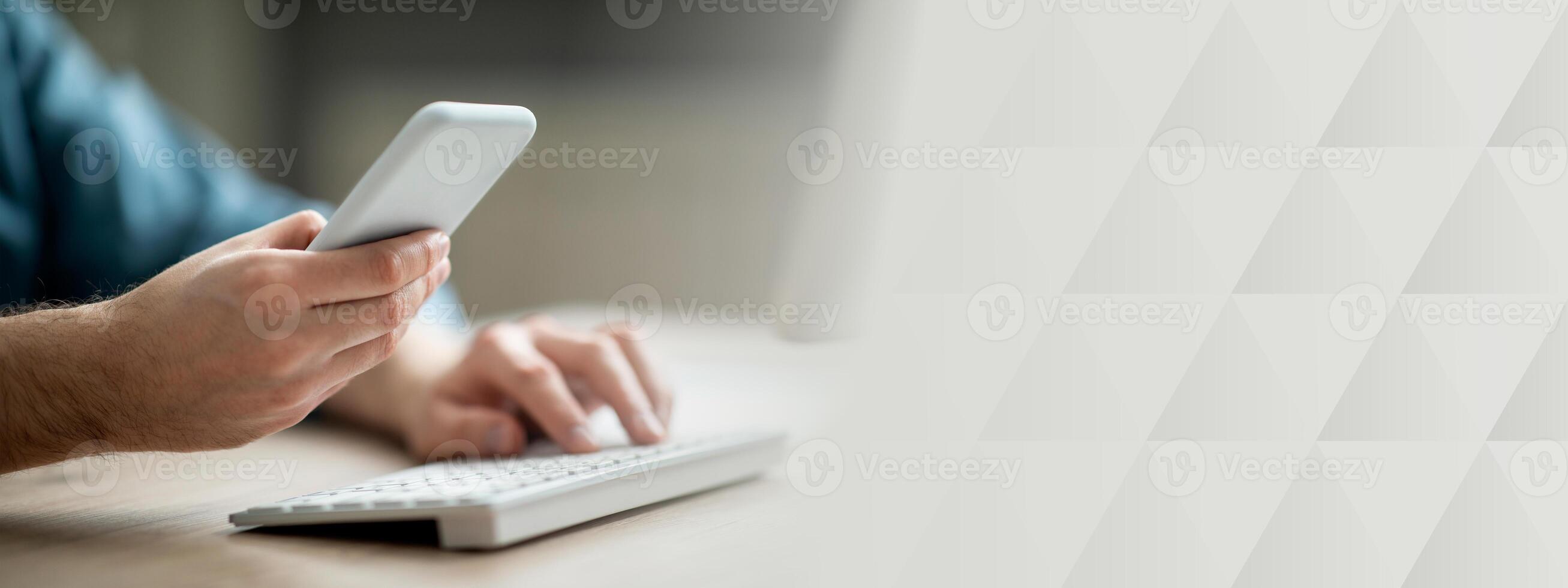 Unrecognizable businessman working with smartphone and computer in office, man hands holding mobile phone and typing on pc keyboard, using modern gadgets for business, cropped shot, closeup photo