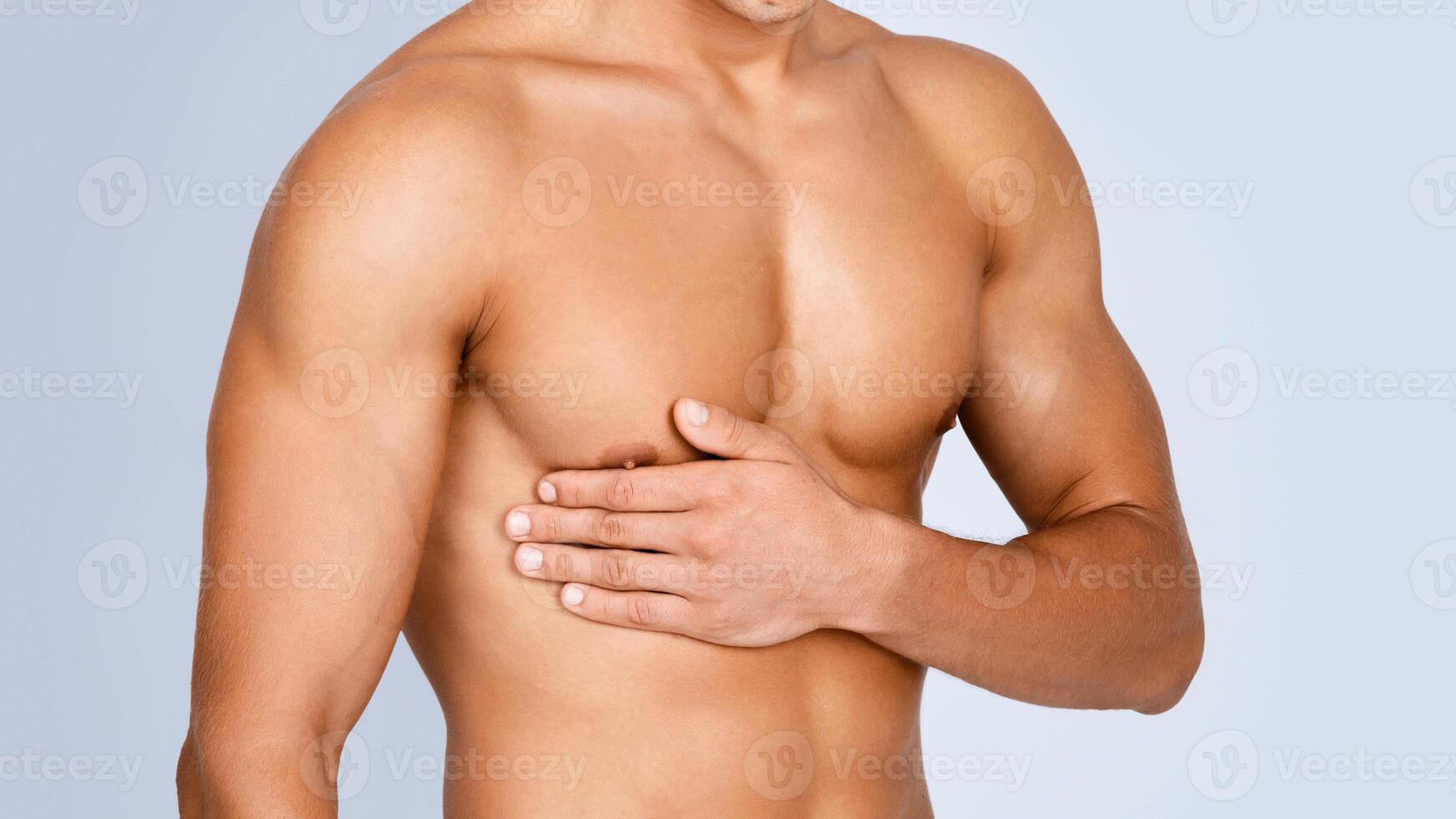 Bodycare Concept. Closeup of unrecognizable strong athletic man with muscular naked torso touching his body isolated over gray studio background. Shirtless guy showing his chest. Sport And Health photo