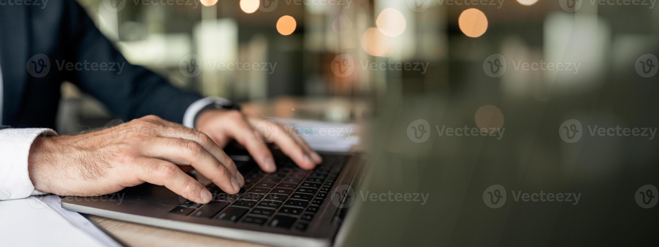 Closeup businessman using laptop, typing on keyboard, writing email, sitting at desk in office, selective focus. Accountant writing financial report, searching information photo