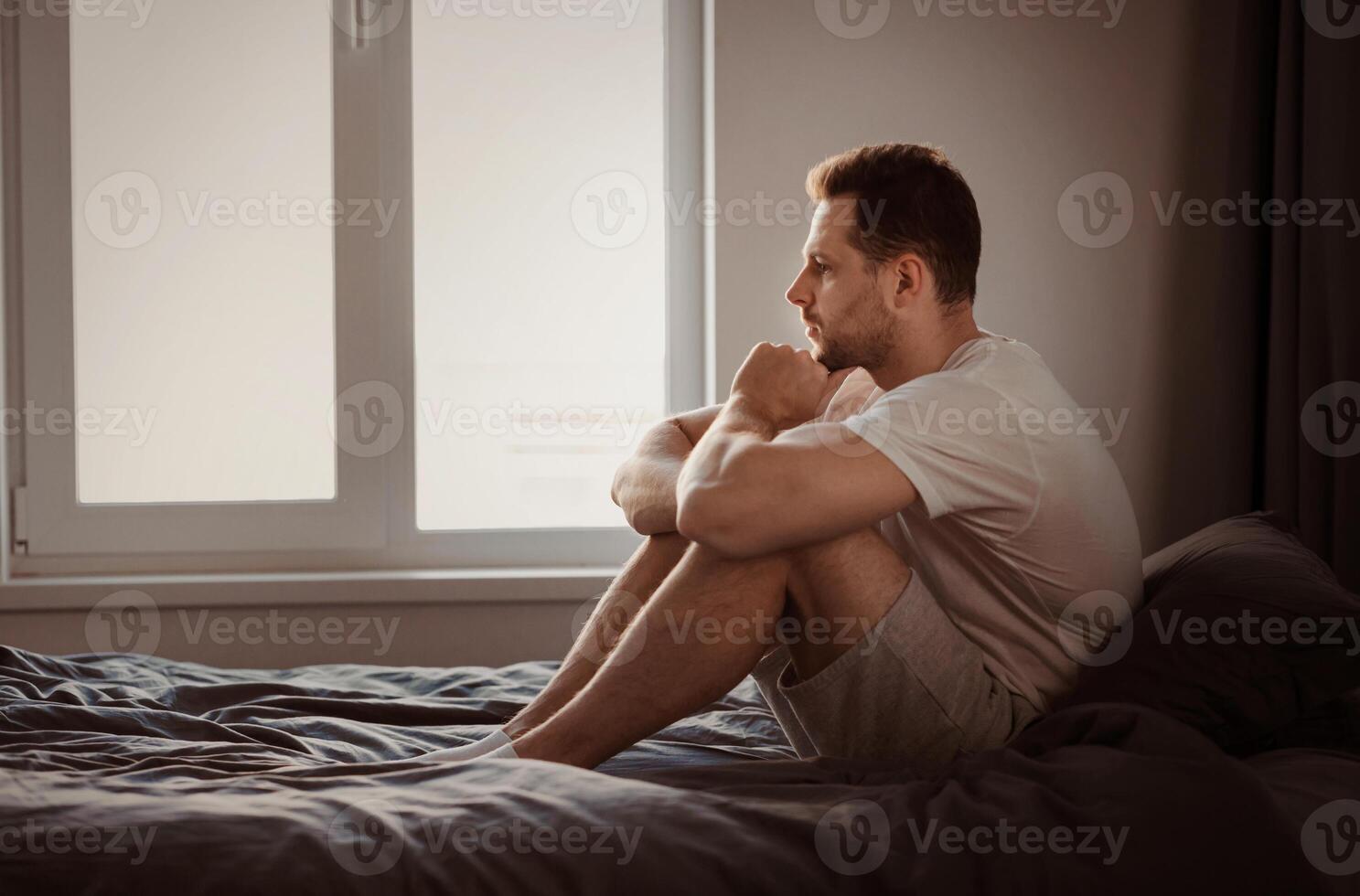 Anxiety Concept. Depressed Man Thinking About Problems Sitting In Bed Indoors. Free Space For Text photo