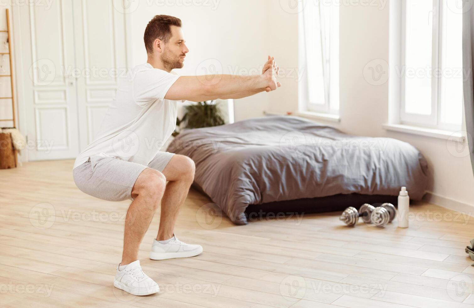 Sporty Guy Doing Two-Legged Squat Exercise Pumping Legs And Buttocks Muscles Training At Home. Fitness Morning, Male Workout Routine Concept. Free Space For Text photo