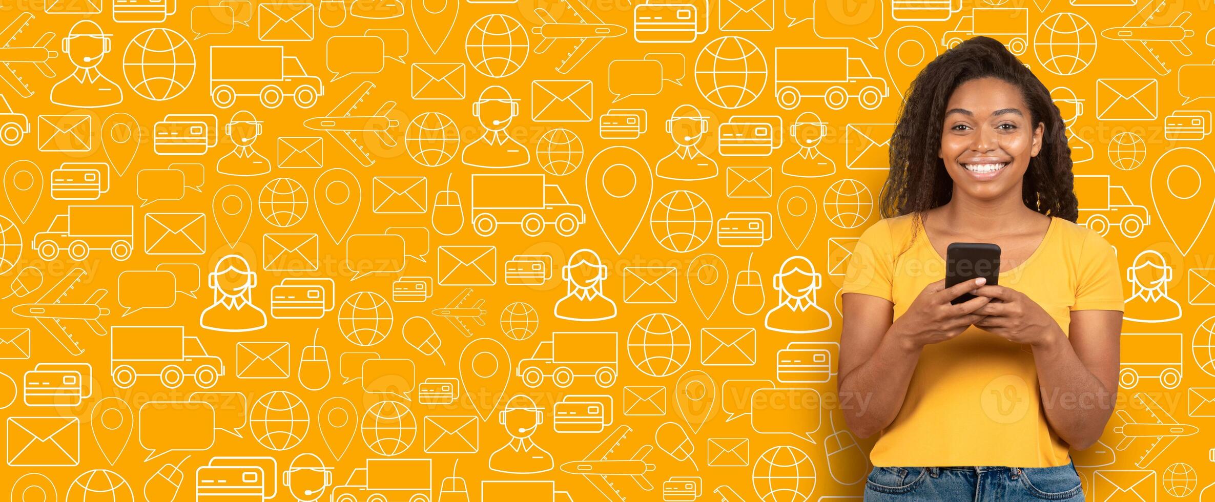 A cheerful buyer stands in front of a vibrant yellow background, engaging with a smartphone to explore online shopping options, highlighting modern commerce trends. photo
