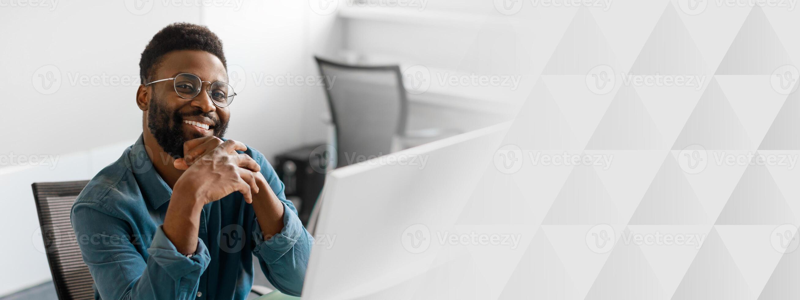 A young African American manager is confidently engaging in work at his modern office. He exudes success and professionalism in his entrepreneurial environment, copy space photo