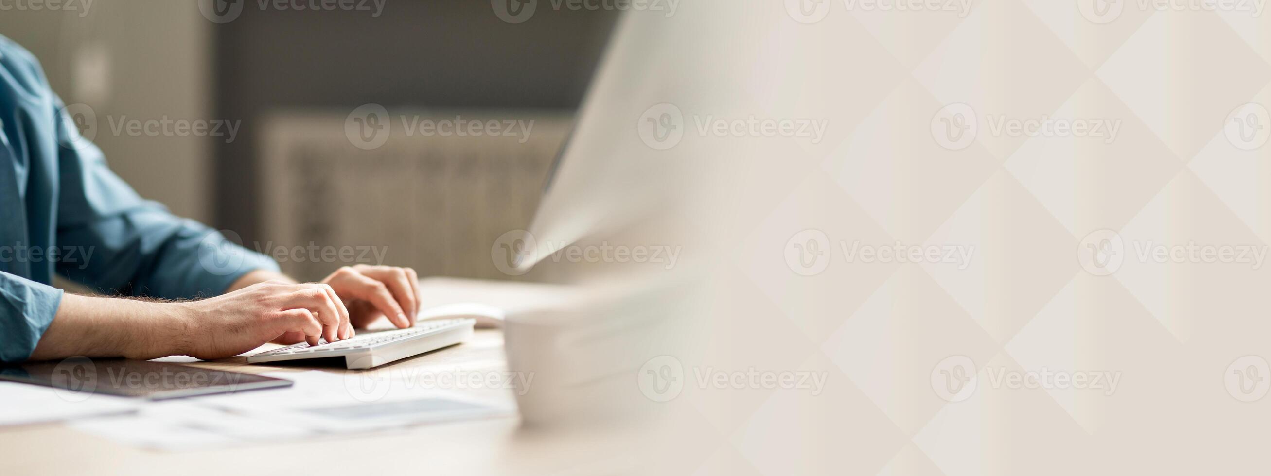Young man sitting at desk and typing on computer keyboard, cropped shot of guy employee using pc in office, working online, businessman answering emails, side view, closeup photo