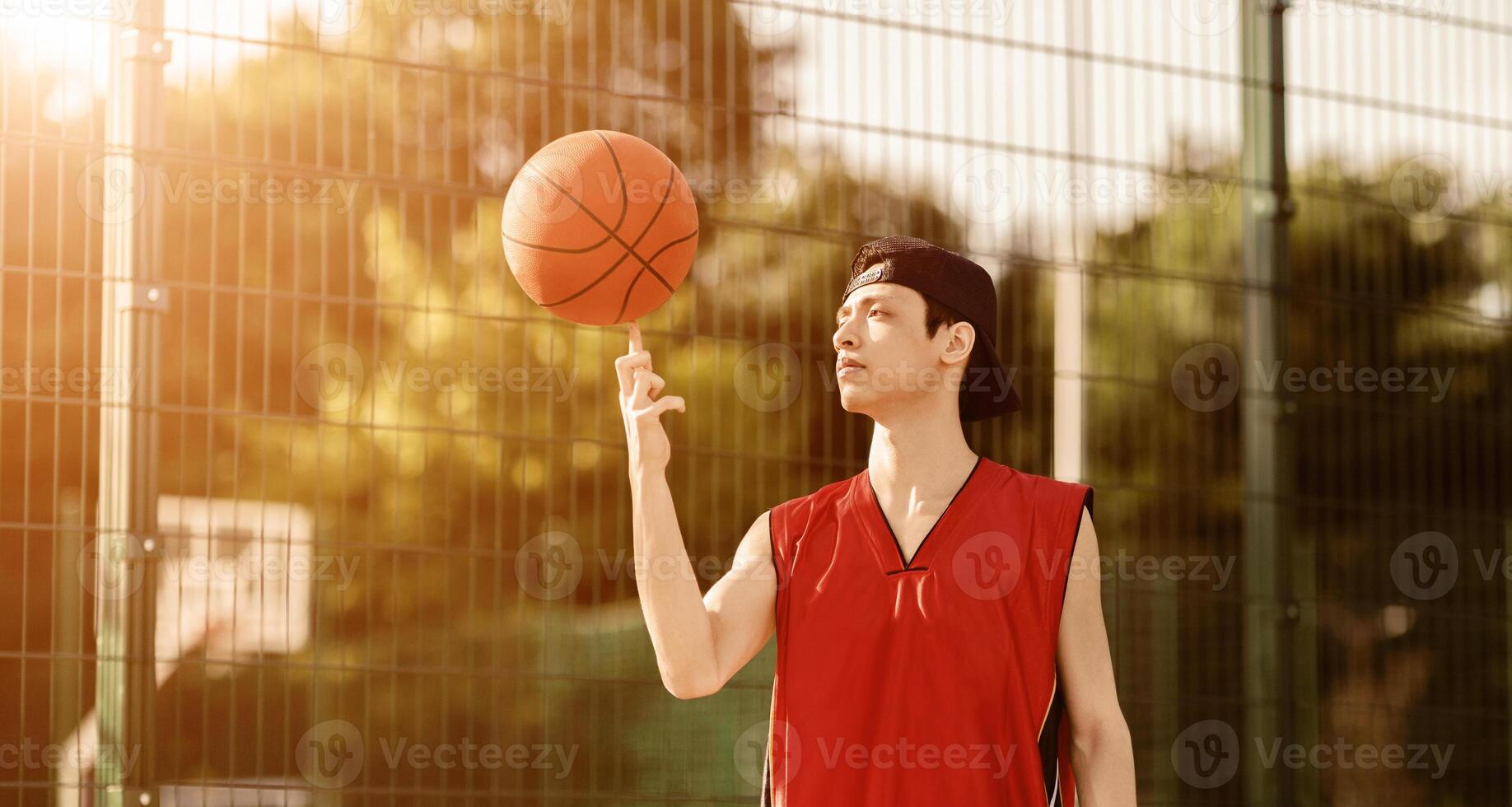 Handsome Asian sportsman with ball on outdoor basketball arena, panorama photo