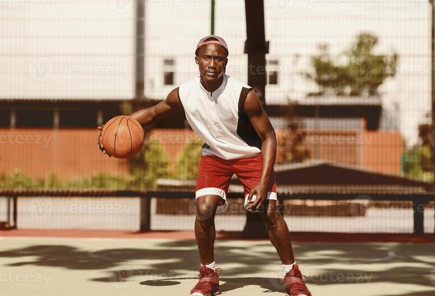 African American player driving ball at outdoor court on hot summer day photo