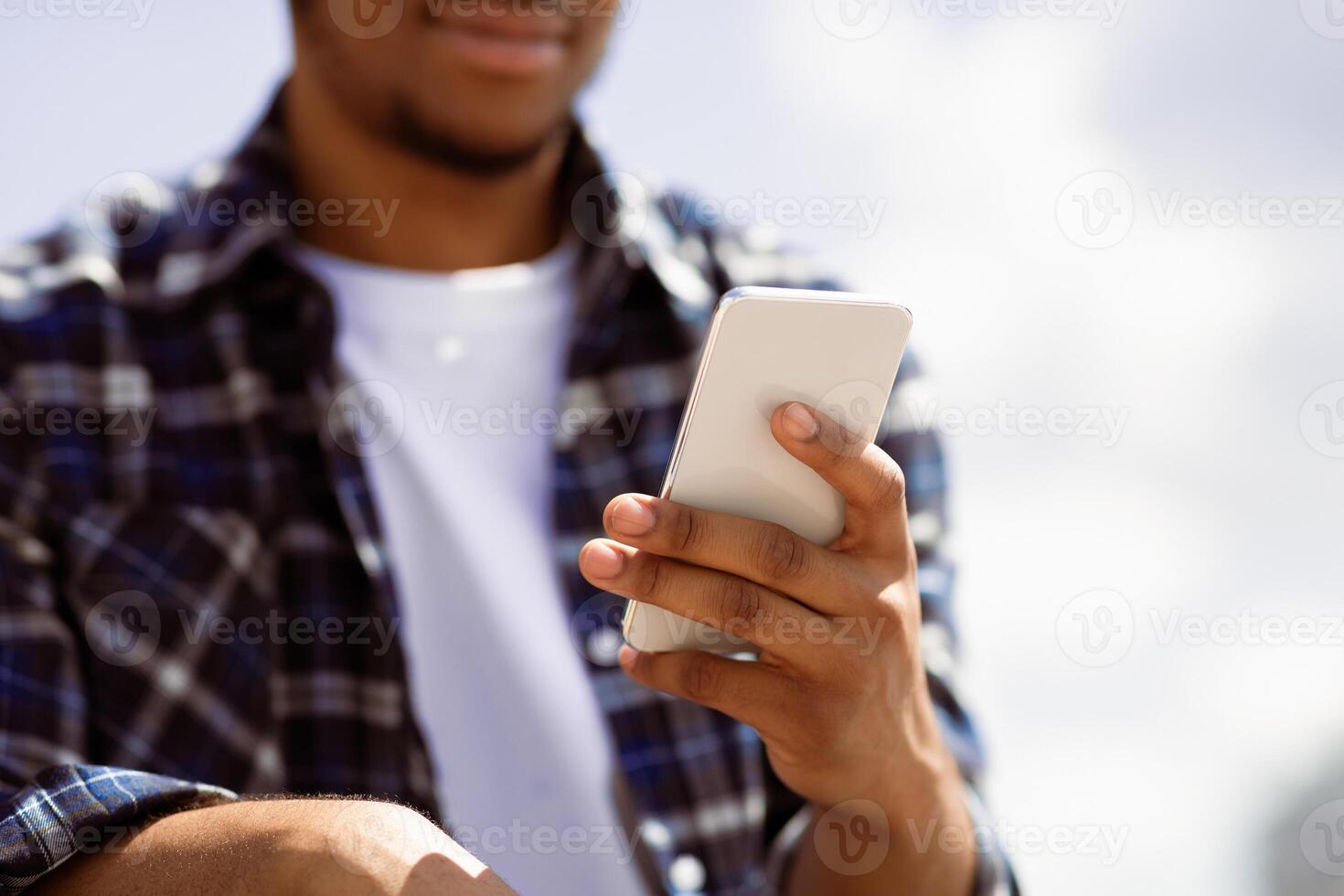 Unrecognizable black guy sending messages online on smartphone, close up, selective focus photo