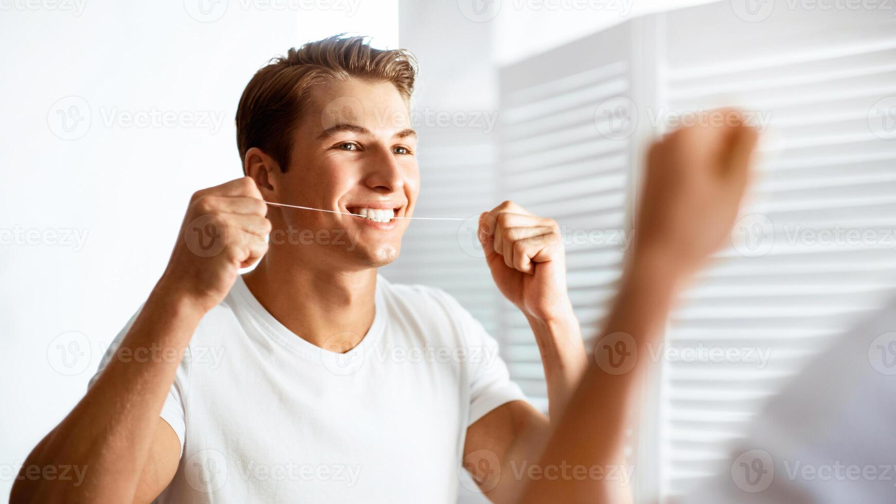 Oral Hygiene Concept. Closeup portrait of guy using dental floss looking in the mirror, banner photo