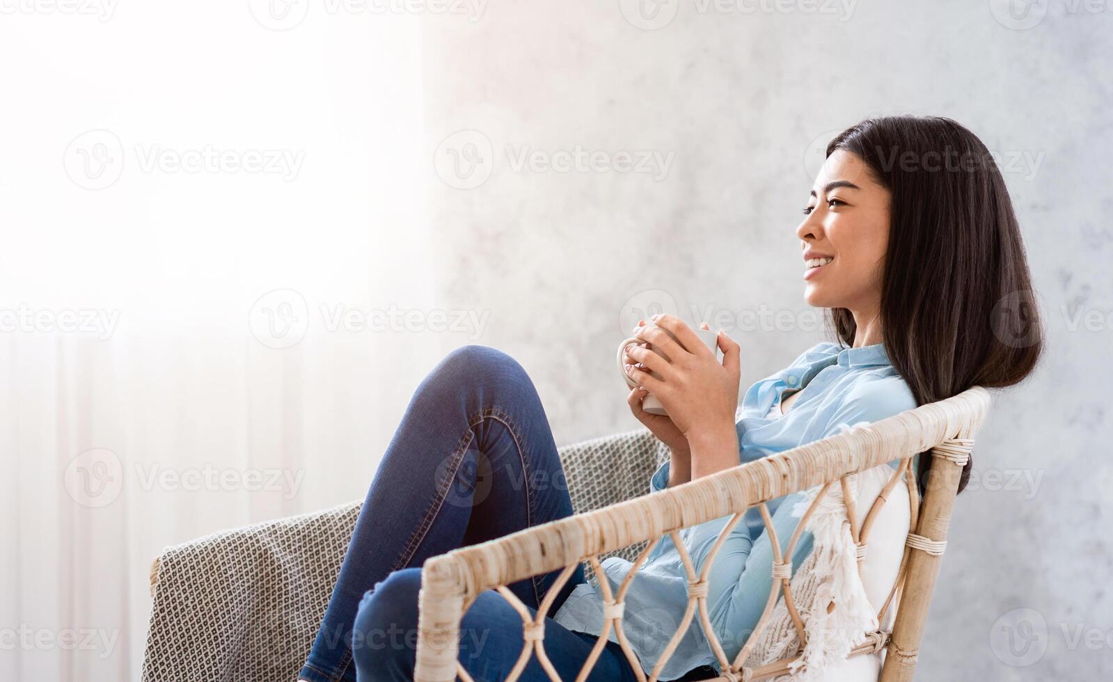 Time To Relax. Calm Asian Girl Enjoying Her Morning Coffee While Sitting In Wicker Chair Near Window At Home, Side View, Panorama With Free Space photo
