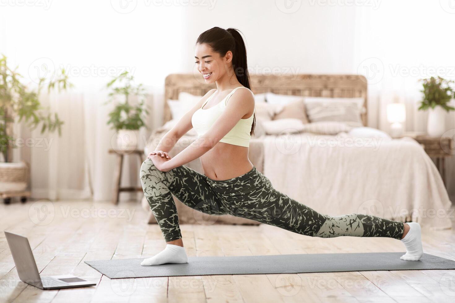 Home Training. Asian Girl Doing Stretching Exercises For Legs In Front Of Laptop, Watching Online Tutorials photo