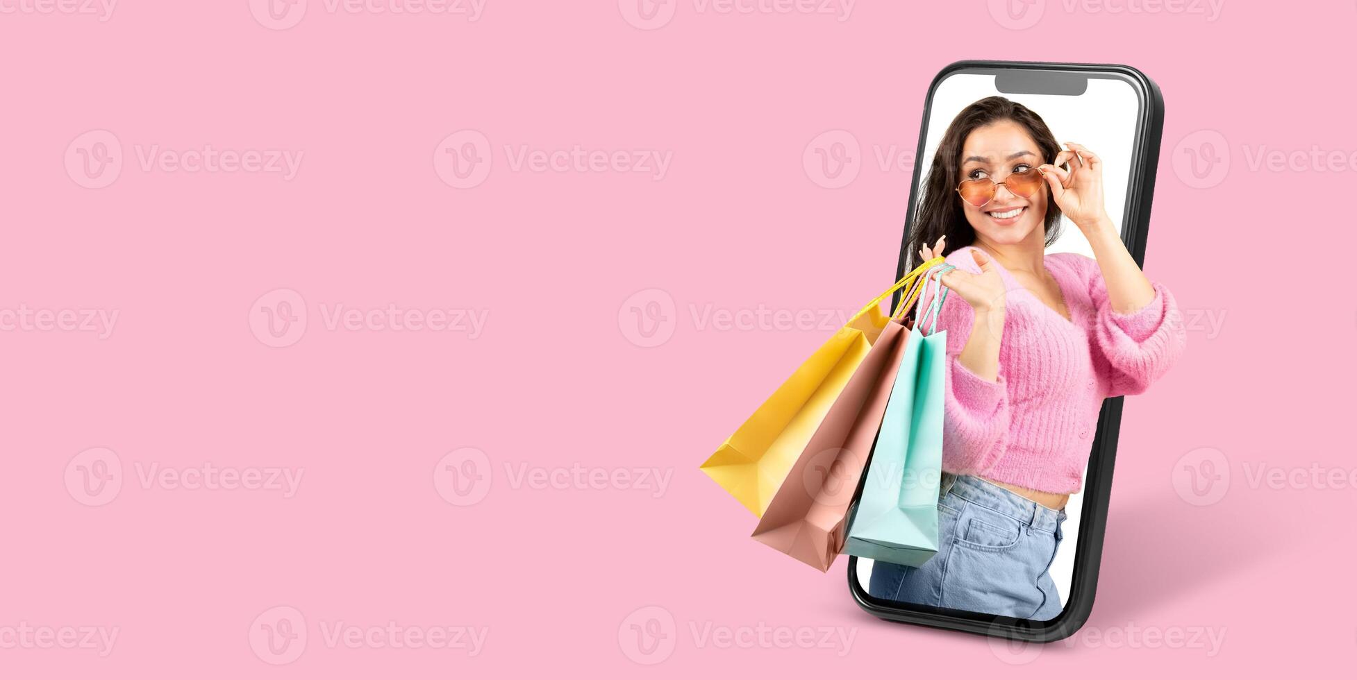 A cheerful customer holds shopping bags while using a smartphone to browse an online store. The vibrant backdrop enhances the theme of modern online commerce. photo