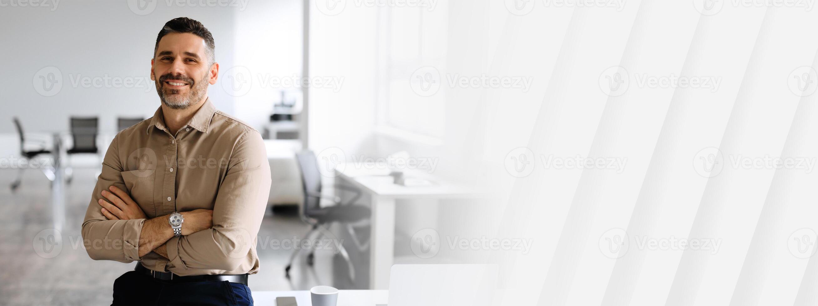 Successful businessman. Confident man in shirt sitting on desk, posing with folded arms, looking and smiling at camera, copy space, place for advertisement photo