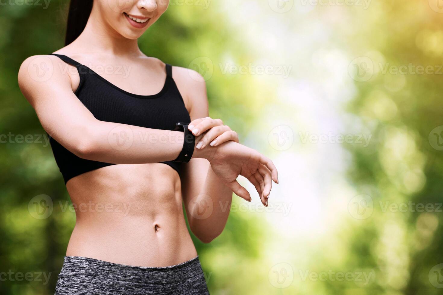 Smiling asian runner girl looking at heart rate monitor on smartwatch after jogging outdoors, checking fitness tracker, copy space photo