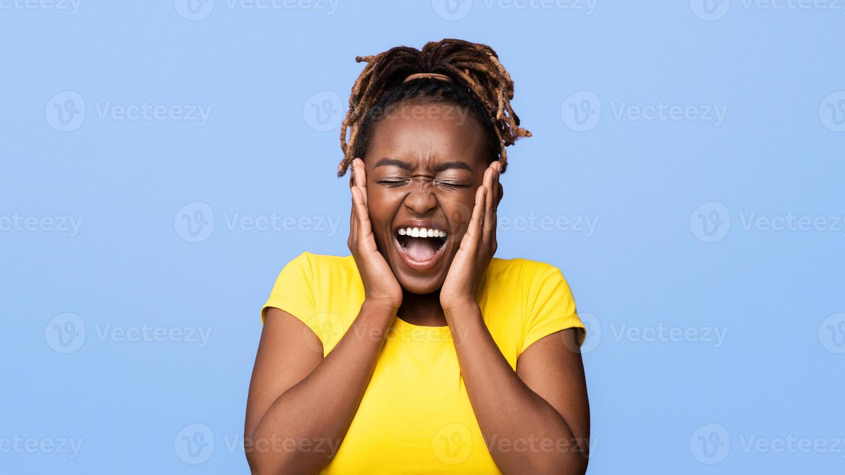 Emotional african girl with closed eyes touching her face and screaming, expressing happiness, purplr background, panorama photo