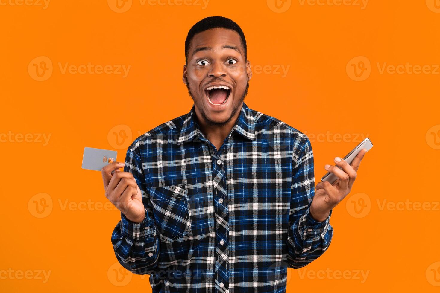 Big Sale. Excited Black Man With Smartphone And Credit Card Shopping Online Using Mobile Banking, Shouting Standing On Yellow Background photo