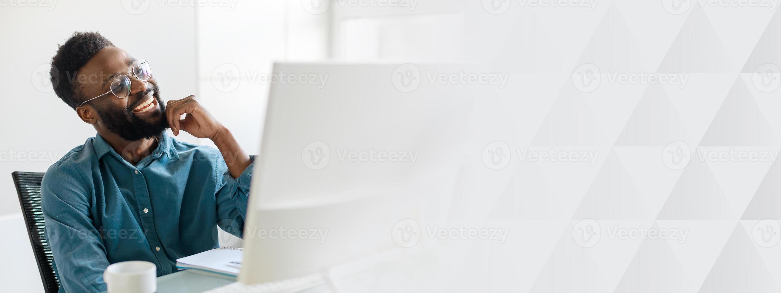 A young male manager, successful and focused, works diligently at his office desk. The modern workspace features a clean design, promoting productivity and creativity, copy space photo