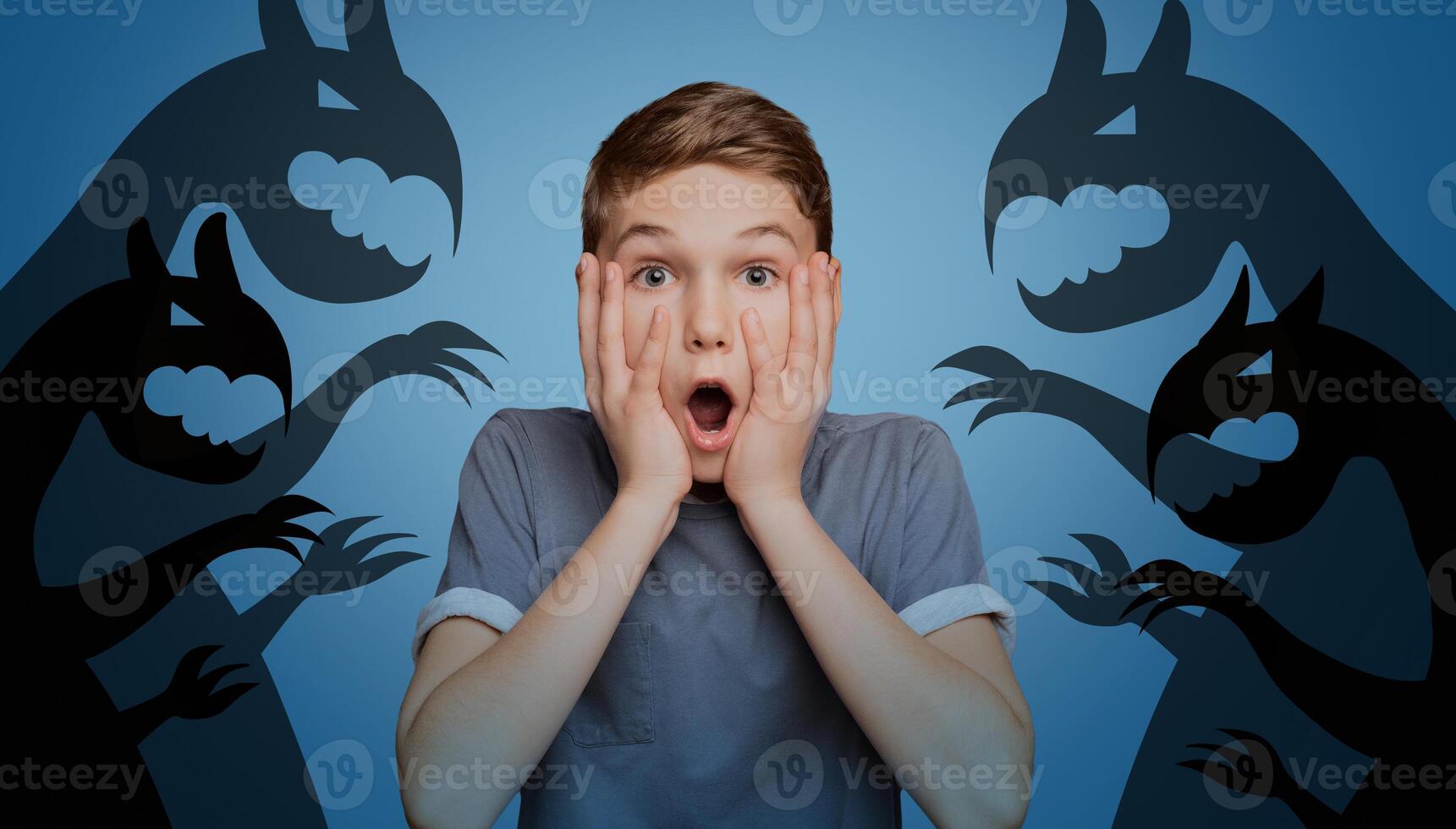 Scared little boy opening mouth and touching his face, afraid of imaginary monsters on orange studio background, banner design. Inner fears, phobias, psychological problems concept photo