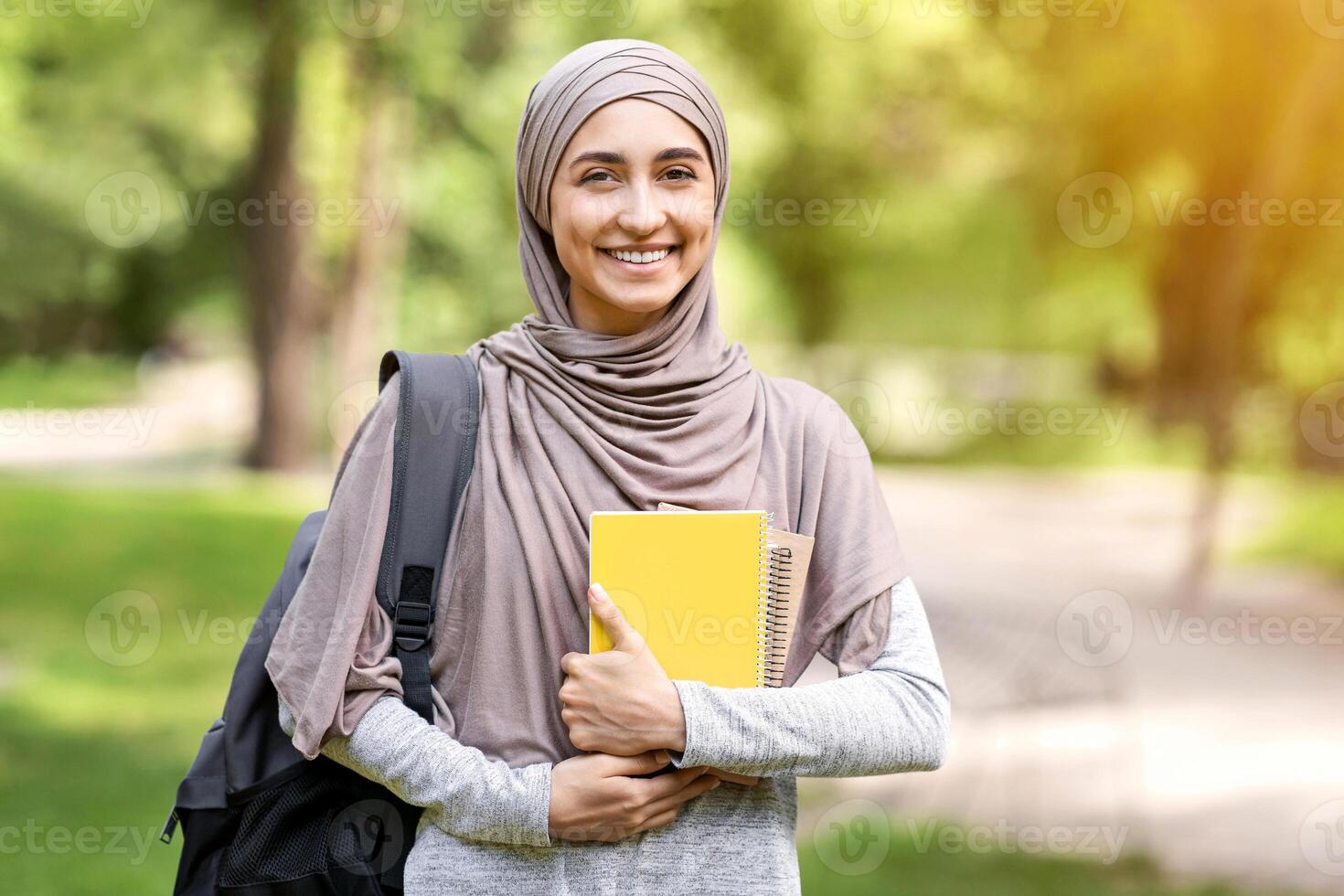 Pretty arab girl student having rest after university at public park, copy space photo
