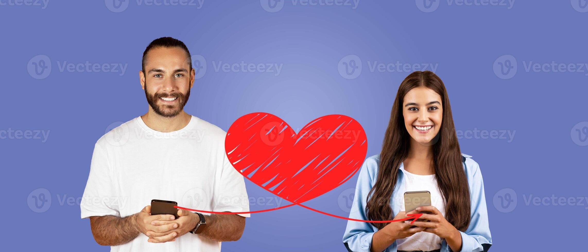 A couple expresses their affection on St. Valentine's Day by using their smartphones to send loving messages. They are smiling and enjoying their connection, isolated against a solid background. photo