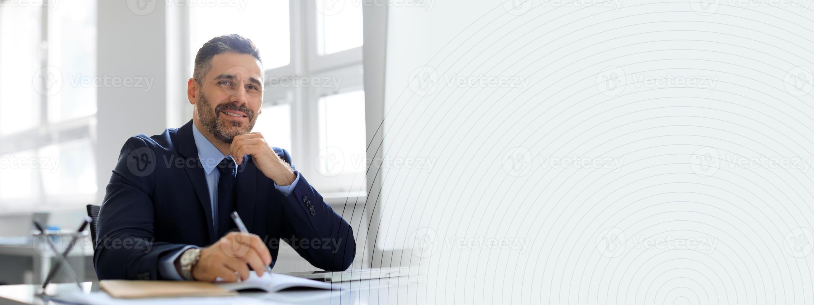 A middle aged businessman sits confidently at his desk in a bright office. He thoughtfully writes in his notebook, embodying success and productivity in a contemporary work environment, copy space photo