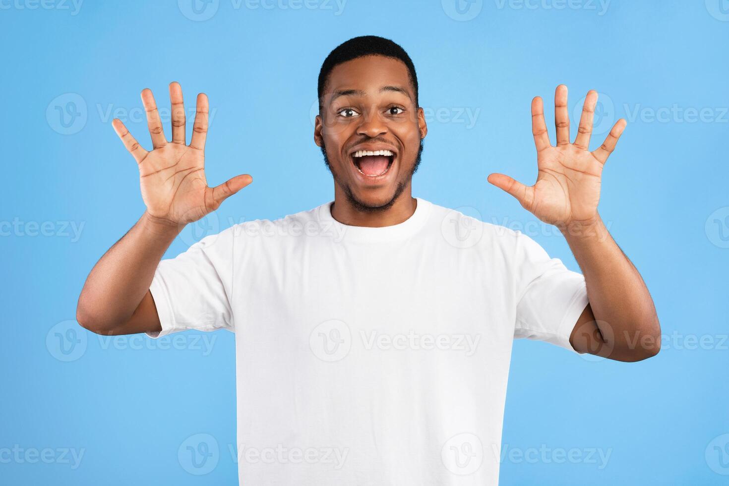 Joyful Black Man Showing Number Ten With Both Hands Smiling To Camera Posing Over Blue Background. Studio Shot photo