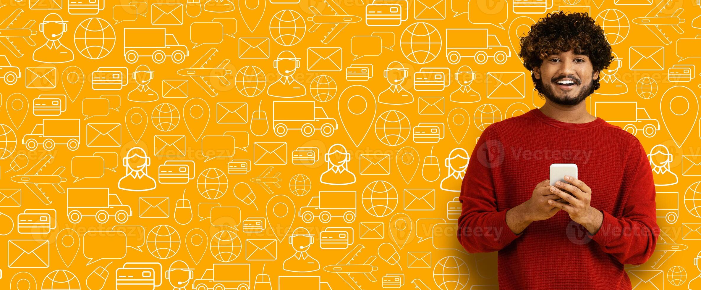 A cheerful buyer stands against a vibrant yellow background filled with delivery icons, holding a smartphone. He is engaged in online shopping and enjoying a seamless experience. photo