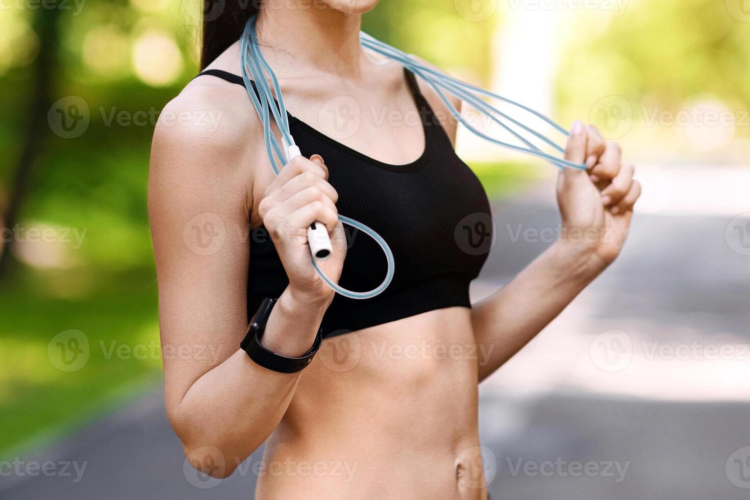 Fit smiling asian woman posing with skipping jump rope outdoors, exercising at public park, enjoying fitness workout photo