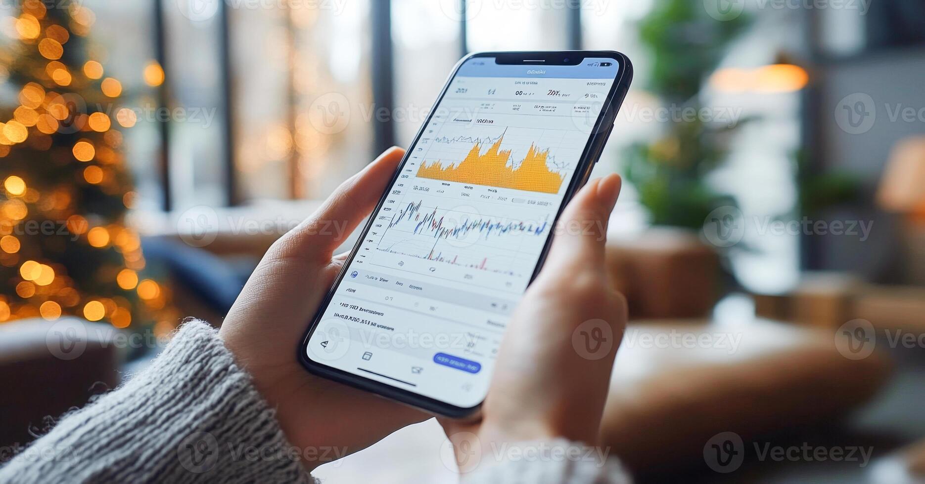 A user interacts with a smartphone displaying banking transaction graphs and statements. The cozy indoor setting is decorated for the holiday season, suggesting a blend of finance and festive cheer. photo